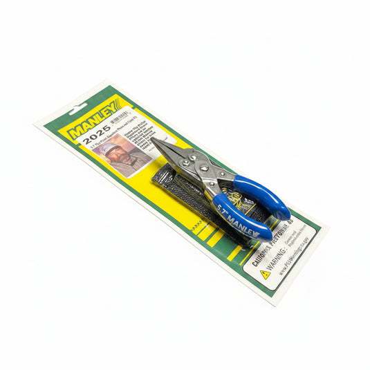 A packaged pair of Stanley 2025 tin shears with blue handles rests on top of a yellow and green product card, placed on a round gray metal stool.