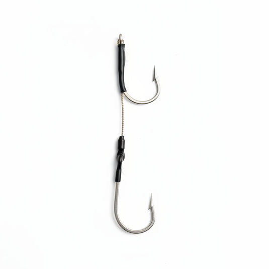 A pair of silver metal fishing hooks with black wrapped sections and a braided cord.
