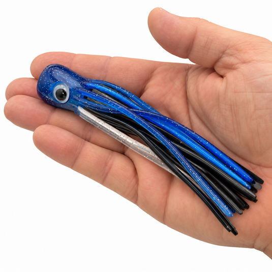 Mold Craft Little Super Chugger 5.5 inch Blue/Silver offshore trolling lure shown in hand for size reference, featuring blue glitter head and multicolor skirt.