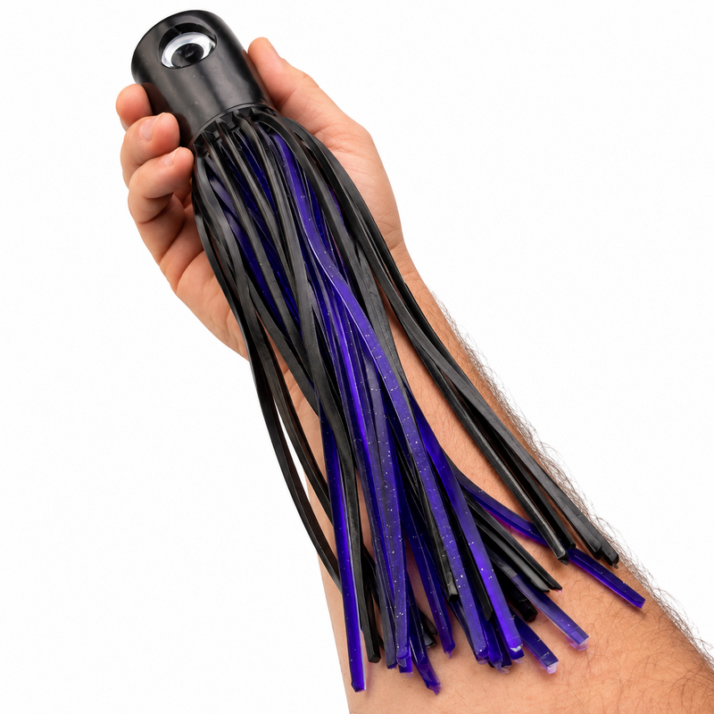 Load image into Gallery viewer, Mold Craft Senior Super Chugger Black/Purple offshore trolling lure held in hand for size reference, showing its black head and purple-and-black skirt.
