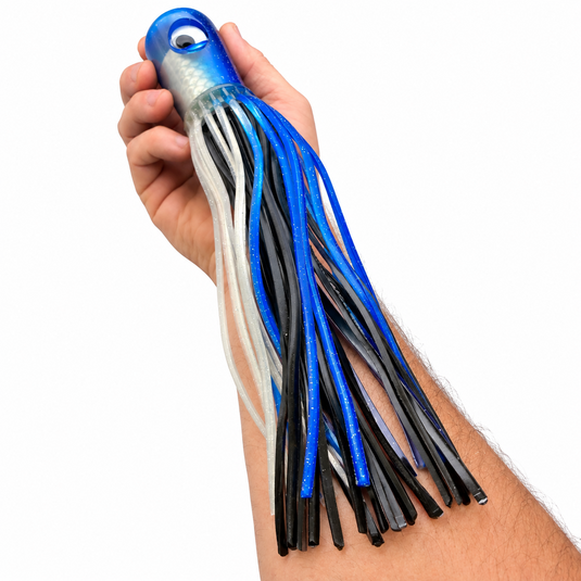 Mold Craft Senior Super Chugger Blue/Silver offshore trolling lure held in hand for size reference, featuring a blue glitter head and blue, black, and silver skirt.