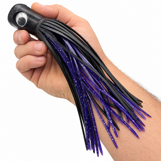 Mold Craft Standard Super Chugger 8¼ inch Black/Purple offshore trolling lure shown in hand for size reference, featuring a black head and black-and-purple glitter skirt.